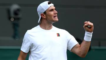 Tenisista Jack Draper w białej koszulce i czapce świętuje wygraną, trzymając rakietę tenisową.