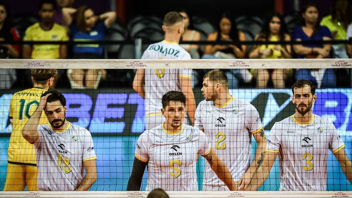 Siatkarze Aluronu CMC Warta Zawiercie w białych koszulkach stoją przy siatce.