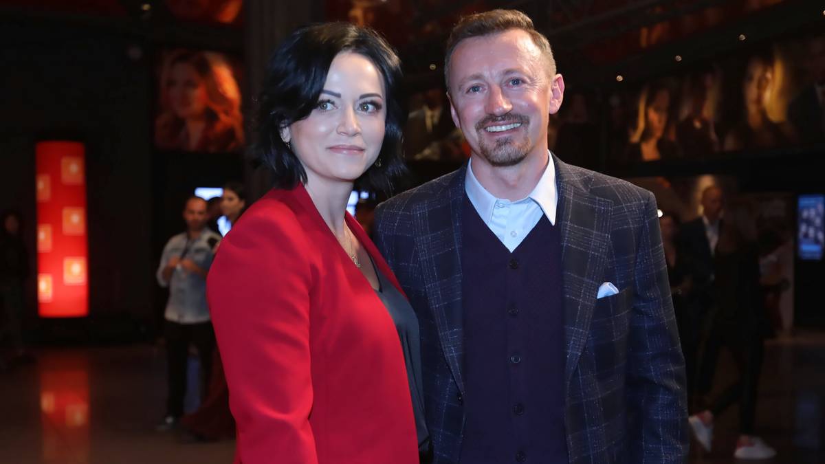 Kobieta w czerwonym żakiecie i mężczyzna w garniturze pozują do zdjęcia.