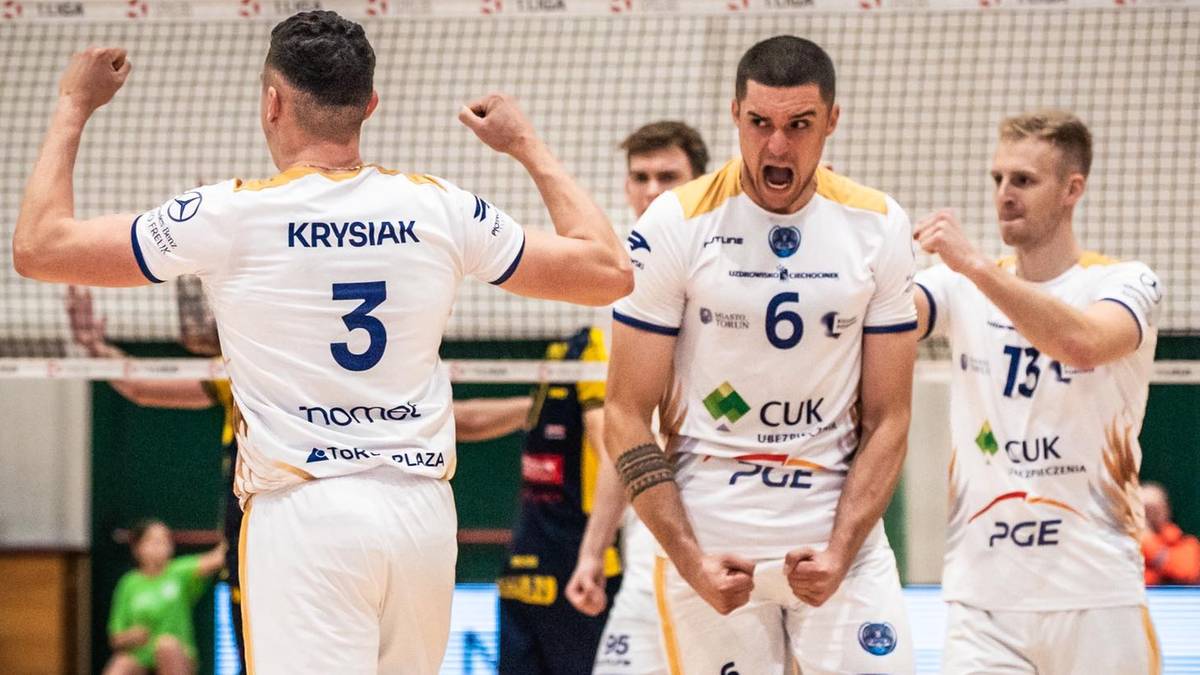 Siatkarze w białych koszulkach z numerami 3 i 6 świętują zwycięstwo na boisku siatkarskim.