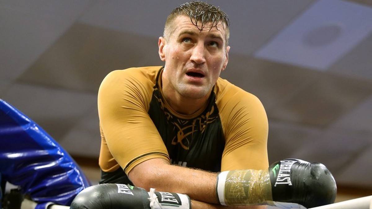 Bokser Mariusz Wach w ringu, ubrany w rękawice bokserskie.