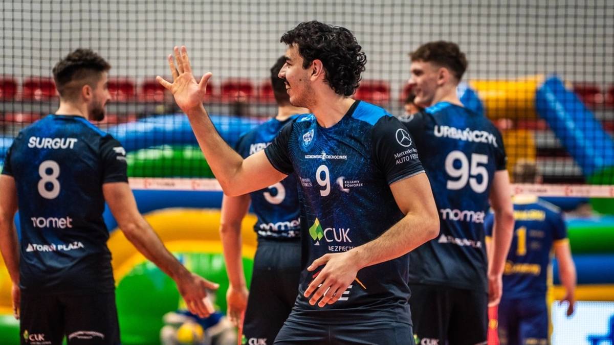 Siatkarze w czarnych strojach z niebieskimi elementami na boisku.