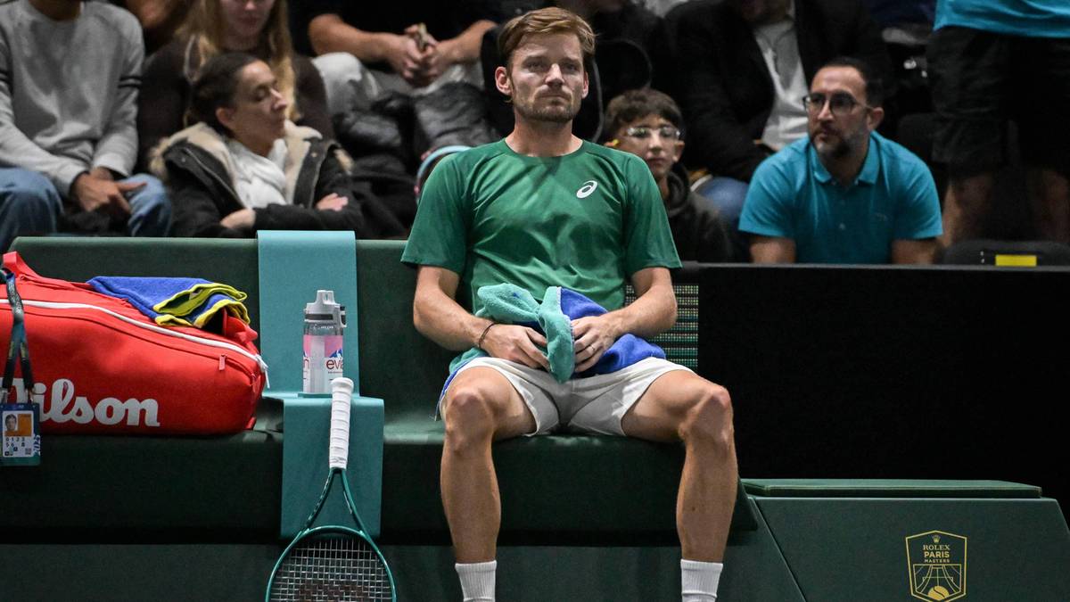 David Goffin siedzący na ławce na korcie tenisowym.