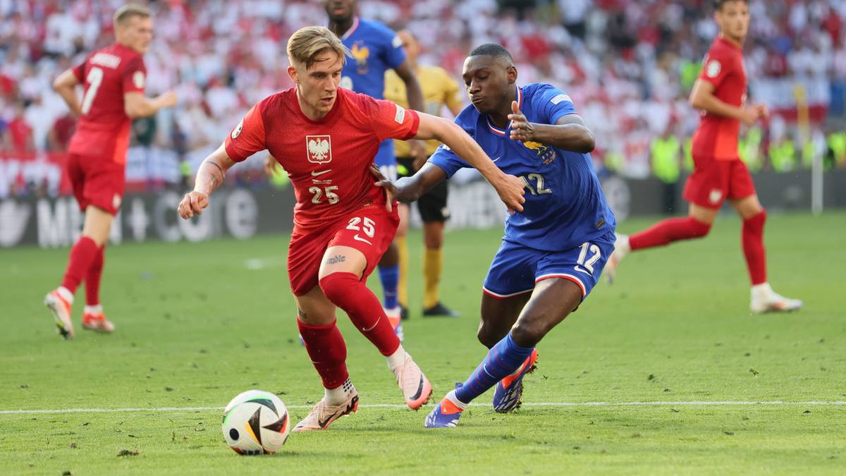 Dwóch zawodników piłki nożnej walczy o piłkę na boisku.