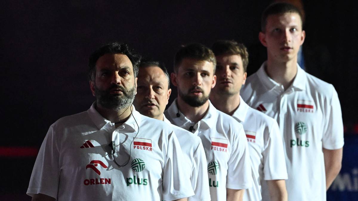 Grupa mężczyzn w białych koszulkach reprezentacji Polski w siatk&oacute;wce, patrzących w kierunku obiektywu.