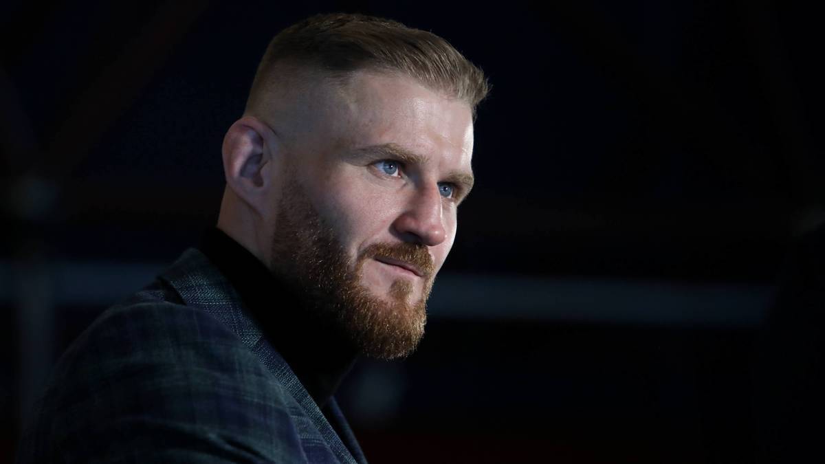 Portret Jana Błachowicza, polskiego zawodnika MMA, z krótką brodą i charakterystyczną fryzurą. Patrzy w bok z lekko uśmiechniętym wyrazem twarzy.