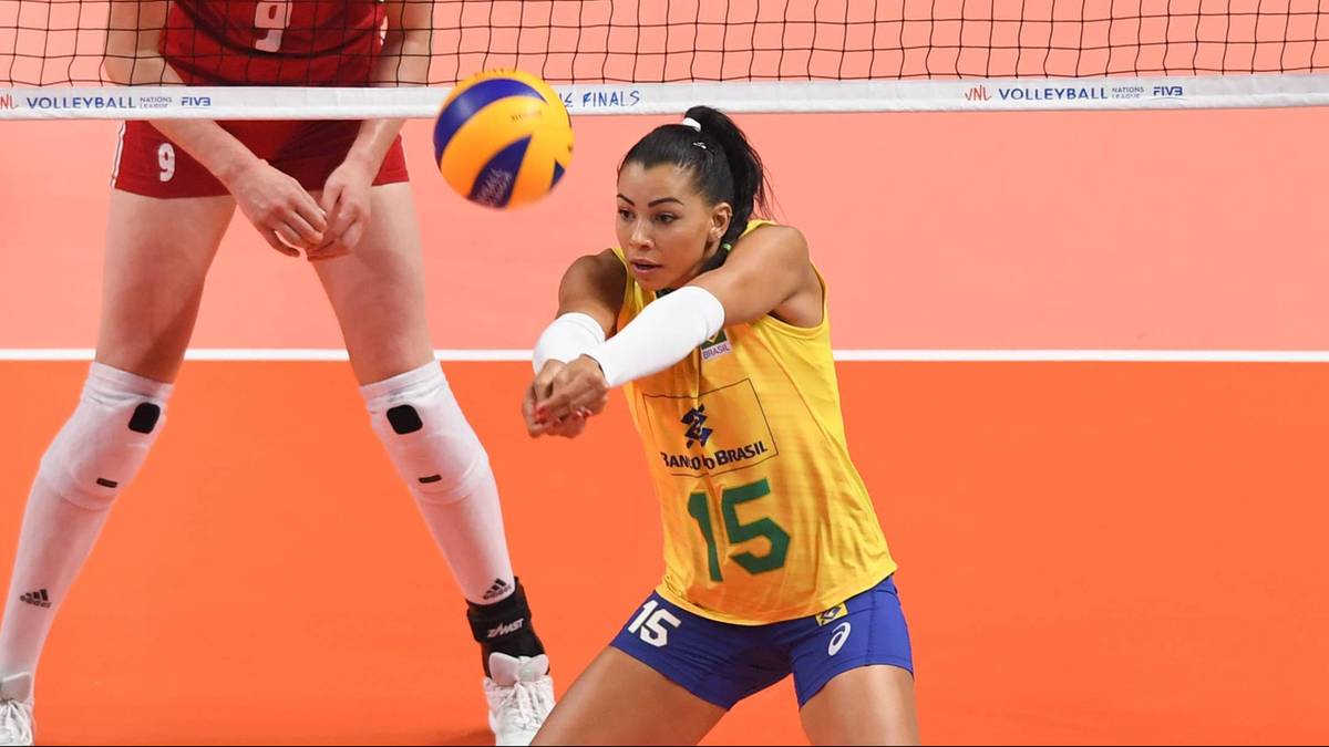 Siatkarka w żółtej koszulce z numerem 15 blokuje piłkę podczas meczu.