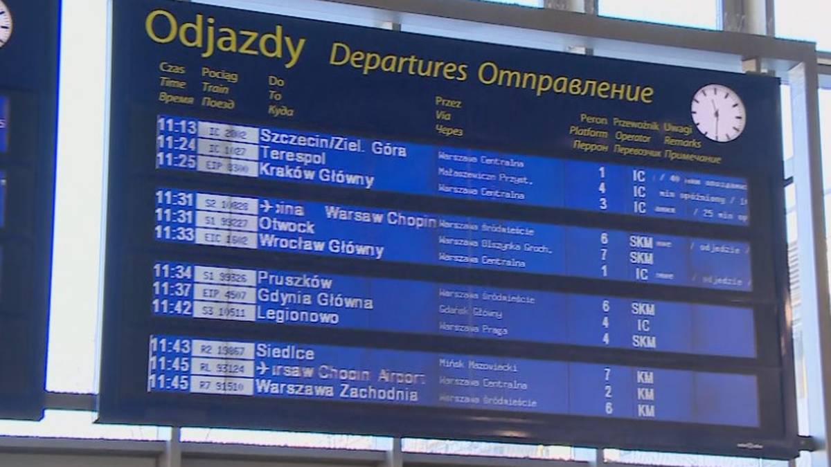 Duża tablica informacyjna na dworcu kolejowym z listą odjazd&oacute;w pociąg&oacute;w, z widocznymi op&oacute;źnieniami.