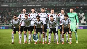 Drużyna piłkarska Legii Warszawa w komplecie, ustawiona do zdjęcia na boisku.