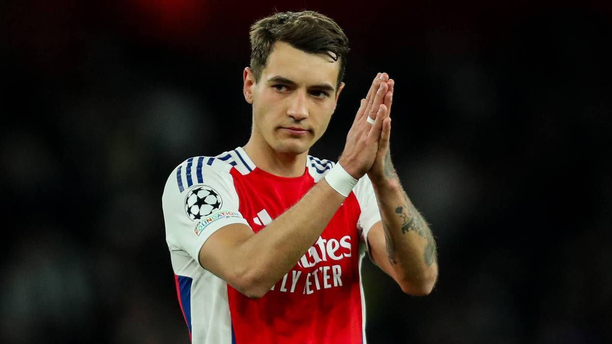 Jakub Kiwior, polski piłkarz w koszulce Arsenalu, z dłońmi złożonymi do oklasków.