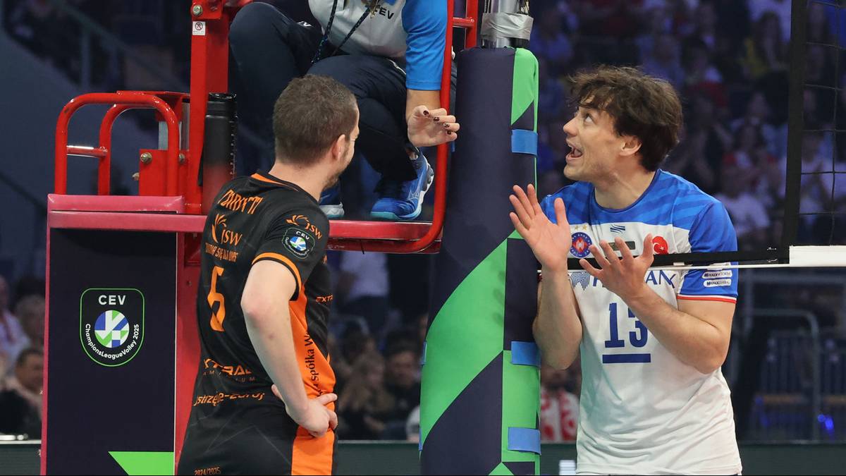 Siatkarz w niebieskiej koszulce z numerem 13 rozmawia z sędzią podczas meczu.