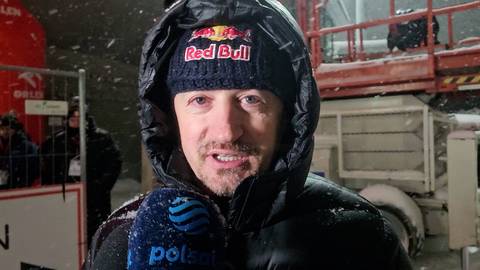 Adam Małysz w czapce Red Bull podczas wywiadu na zewnątrz w zimowej scenerii.