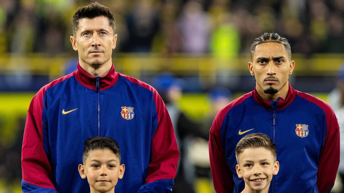 Dwóch piłkarzy FC Barcelony, Robert Lewandowski i Raphinha, stoi z dziećmi w strojach sportowych.