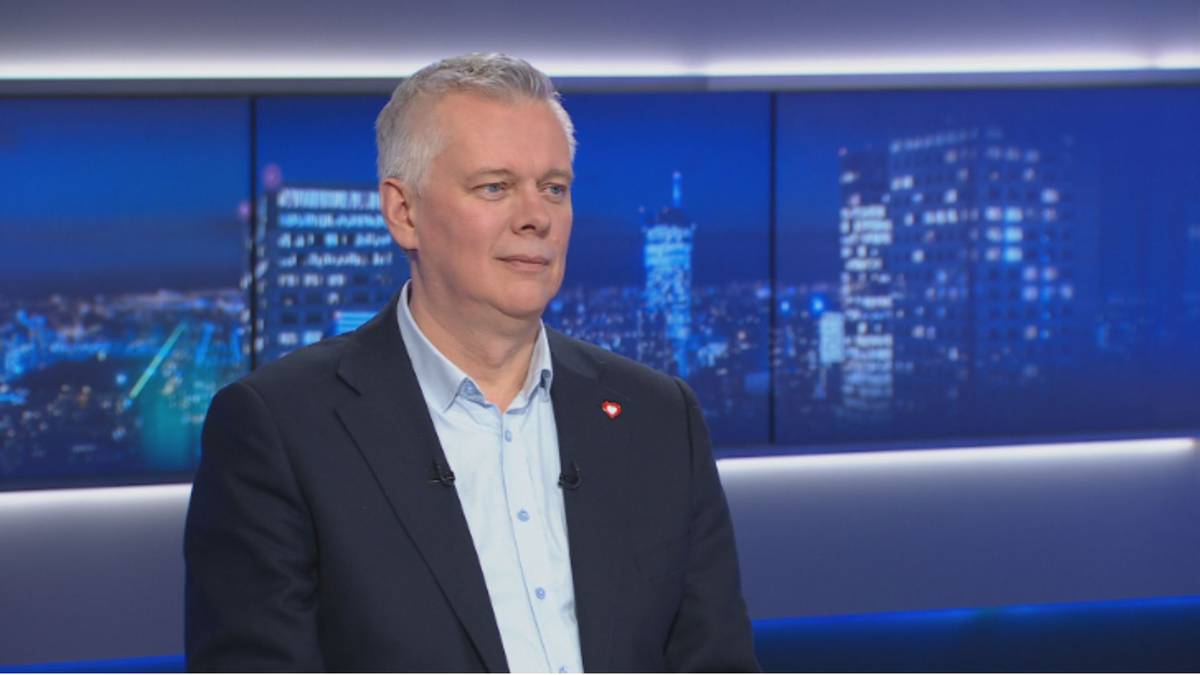 Mężczyzna w średnim wieku w garniturze przed ekranem z nocnym miastem.