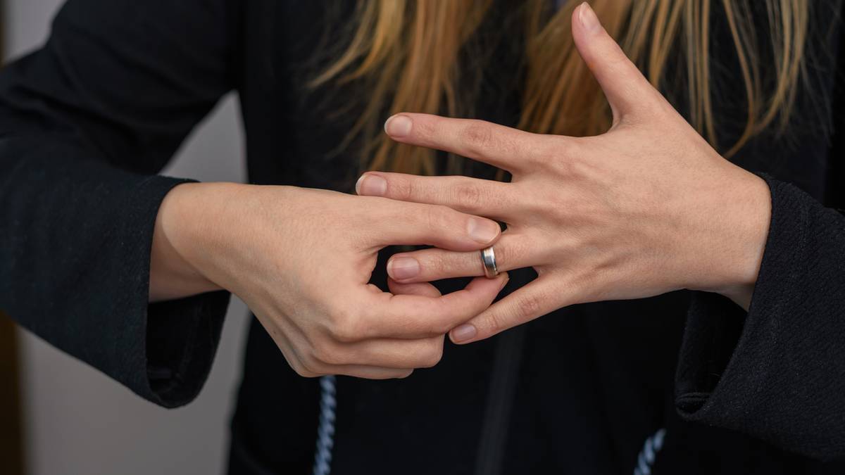 Dłoń kobiety z obrączką na serdecznym palcu, zdejmująca ją.