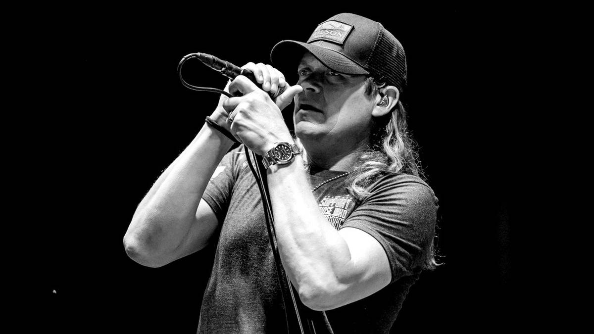 Brad Arnold, wokalista 3 Doors Down, śpiewający do mikrofonu na scenie.