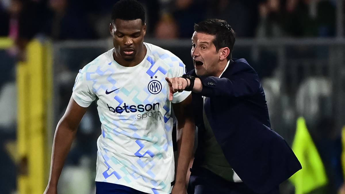 Dw&oacute;ch mężczyzn w strojach piłkarskich, zawodnik Interu Mediolan i trener, rozmawiają na boisku.