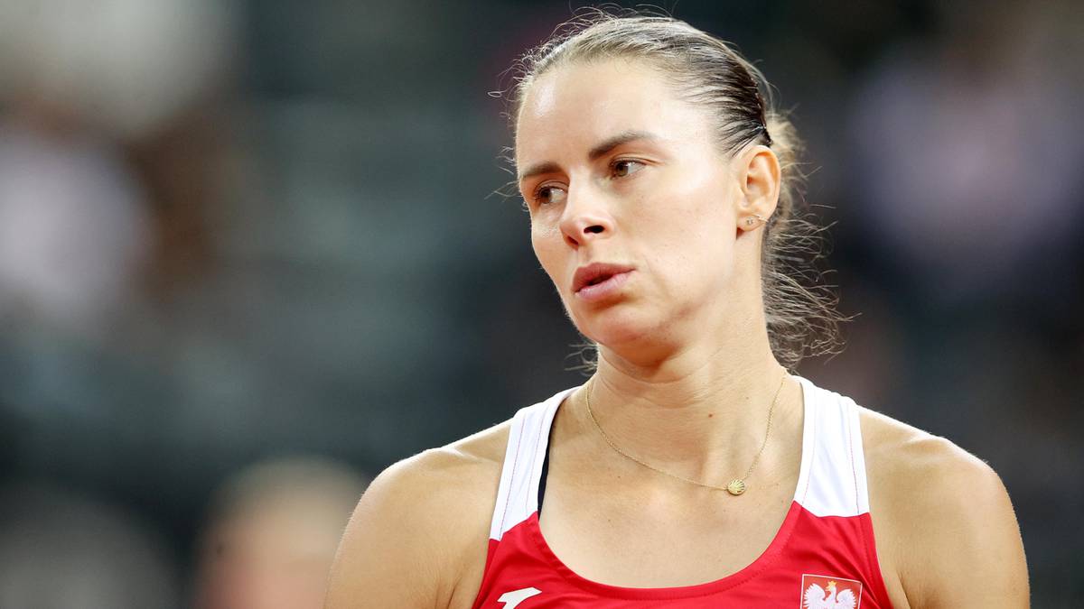 Portret kobiety sportowca w stroju sportowym, z widocznym zamyślonym wyrazem twarzy.
