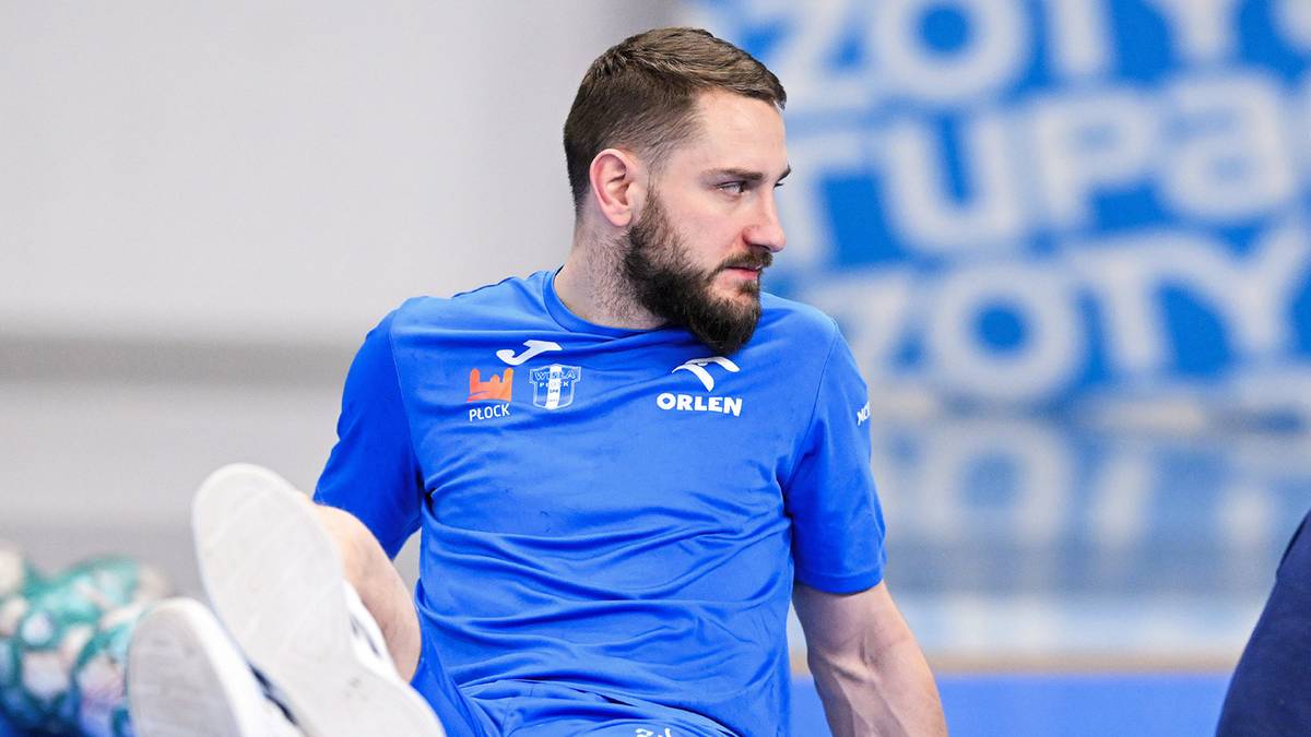 Mężczyzna w niebieskiej koszulce sportowej rozciąga nogę.