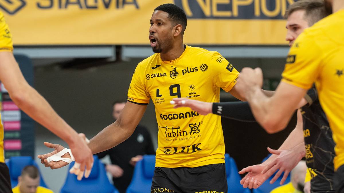 Siatkarze w żółtych strojach podczas meczu, jeden z zawodników z numerem 9 na koszulce udziela wskazówek zespołowi.