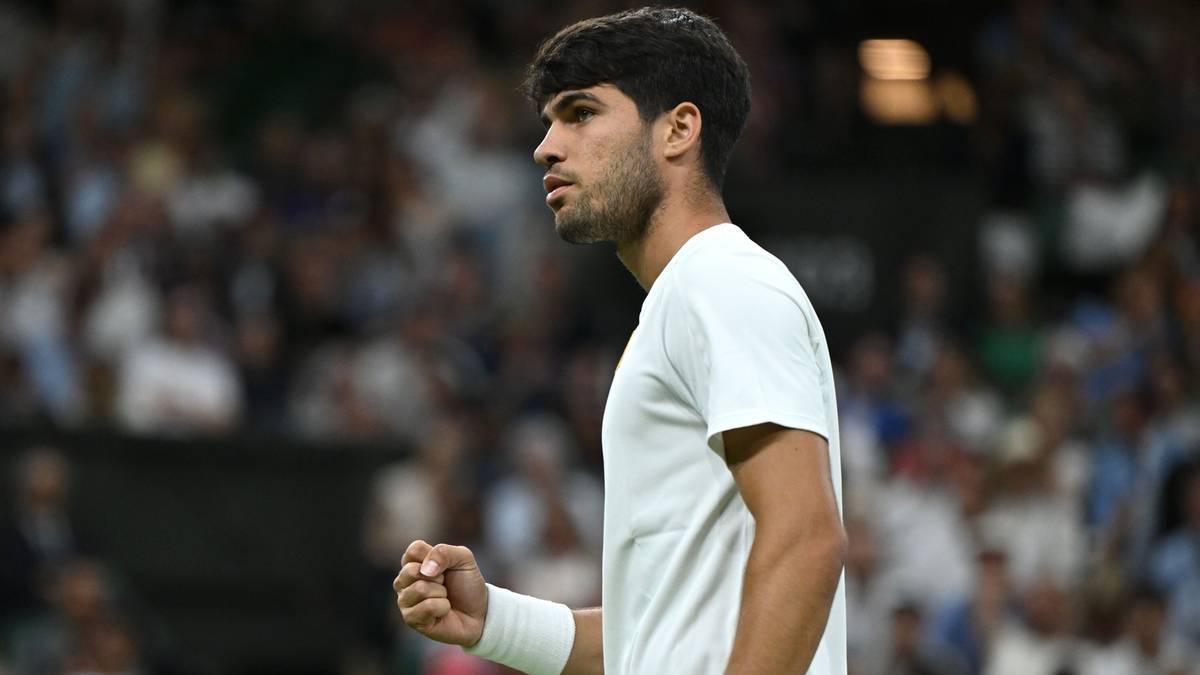 Carlos Alcaraz, tenisista, w białej koszulce, z zaciśniętą pięścią, podczas meczu.