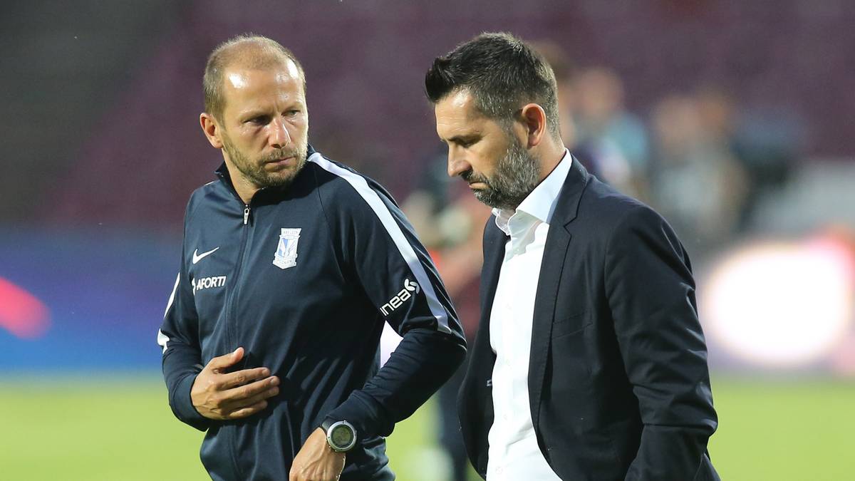 Dw&oacute;ch mężczyzn w strojach sportowych na boisku piłkarskim.