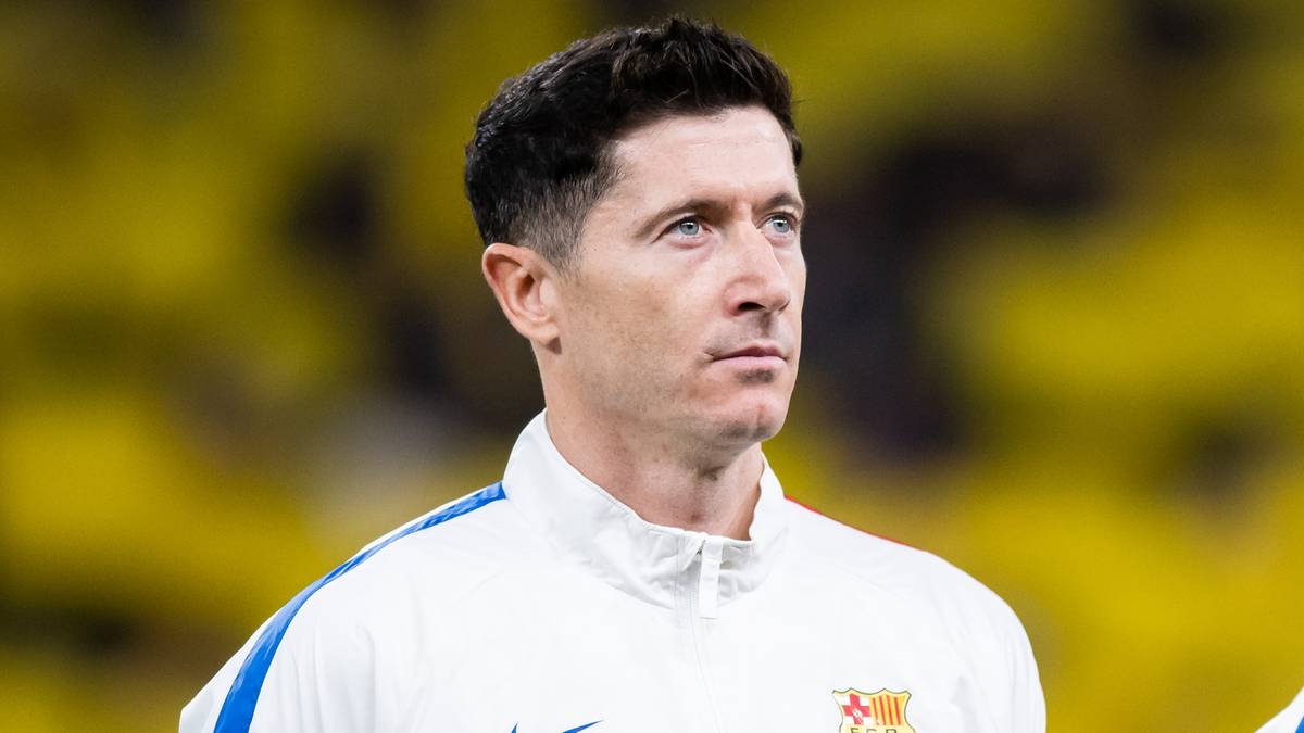 Portret mężczyzny w białej bluzie z niebieskimi pasami i herbem klubu piłkarskiego.