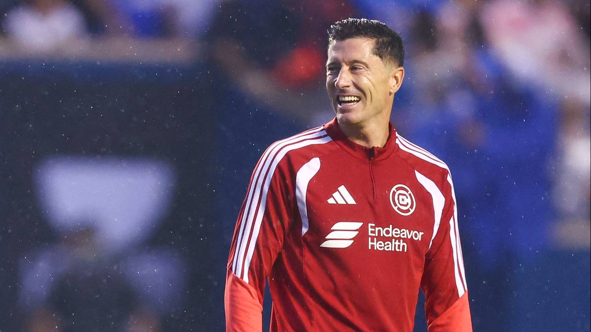 Robert Lewandowski uśmiecha się, ubrany w czerwoną koszulkę piłkarską.