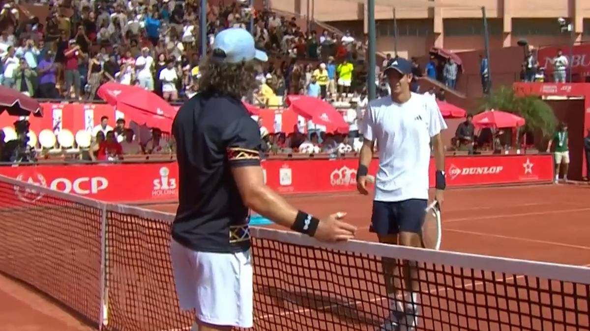 Dw&oacute;ch tenisist&oacute;w na korcie, jeden po drugim, po zakończeniu finałowego meczu.