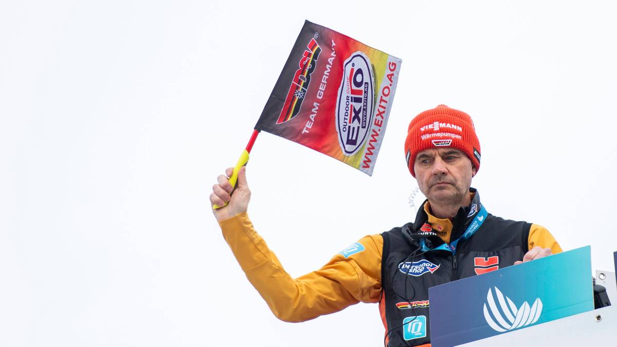 Mężczyzna w czerwonej czapce i ż&oacute;łtej kurtce podnosi flagę z logo EXPO