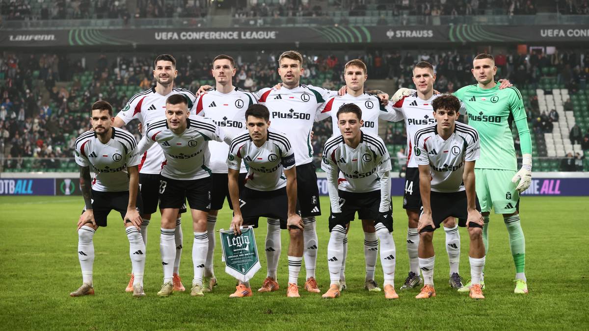 Drużyna piłkarska Legii Warszawa w komplecie, ustawiona do zdjęcia na boisku.