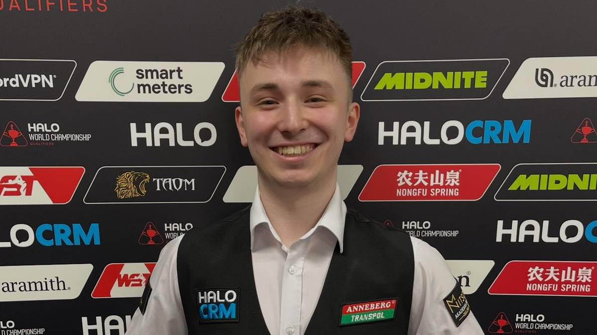 Antoni Kowalski, polski snookerzysta, stojący przed ścianką z logotypami sponsor&oacute;w i napisem "WORLD CHAMPIONSHIP QUALIFYING", uśmiechnięty, pokazujący kciuki do g&oacute;ry.