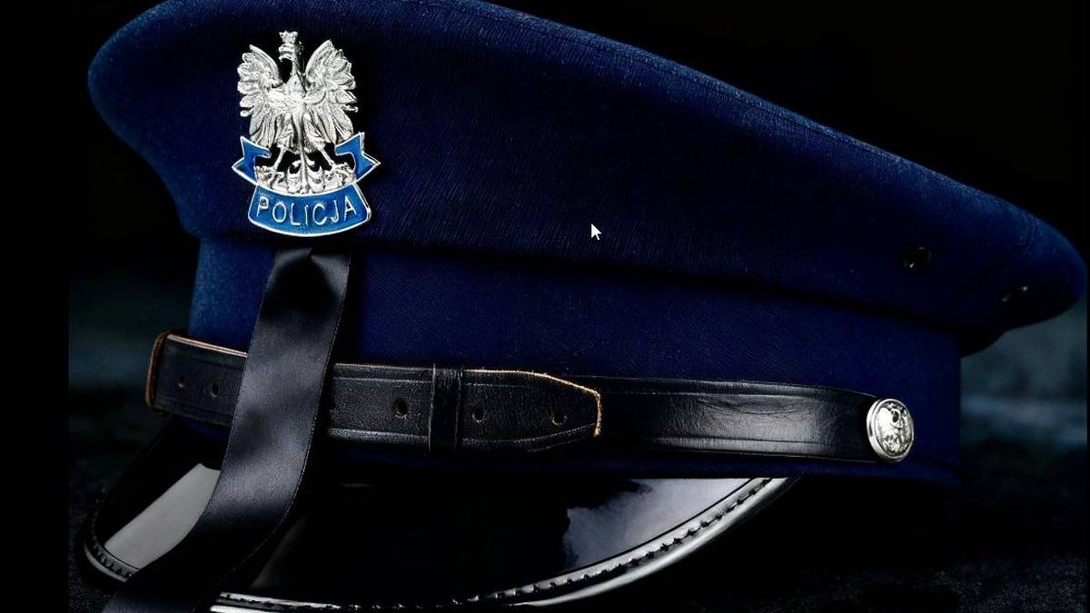 Granatowa czapka policyjna z orłem na tle tarczy z napisem "POLICJA".