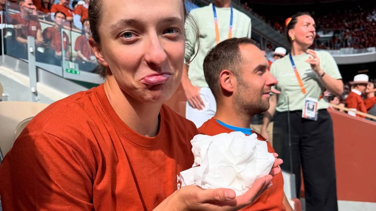 Iga Świątek, tenisistka, z wyrazem wzruszenia na twarzy, trzyma w dłoni białą chusteczkę.