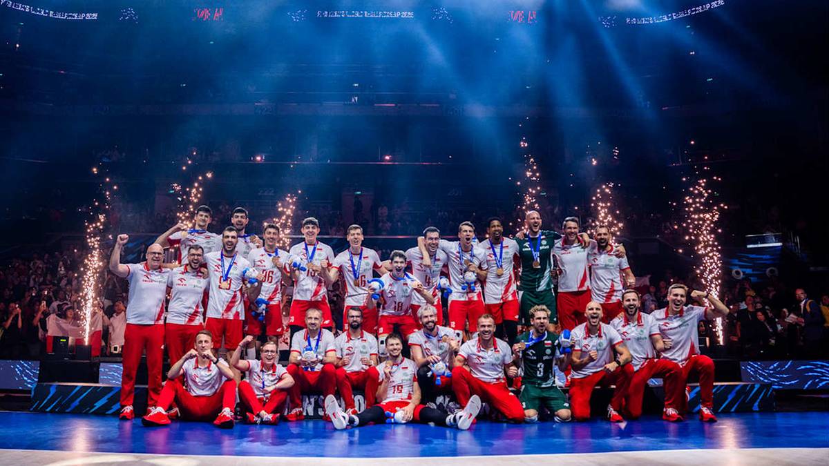 Reprezentacja Polski w siatkówce świętuje zdobycie brązowego medalu na tle fajerwerków.