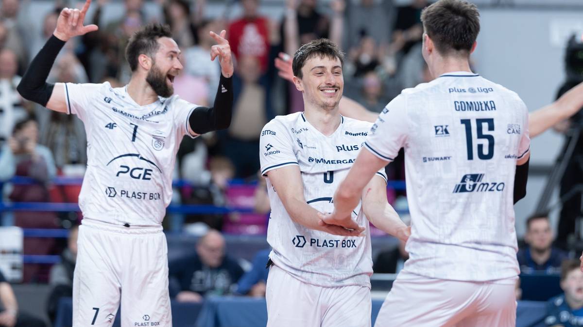 Trzech siatkarzy w białych strojach cieszy się z wygranej akcji, podając sobie ręce.