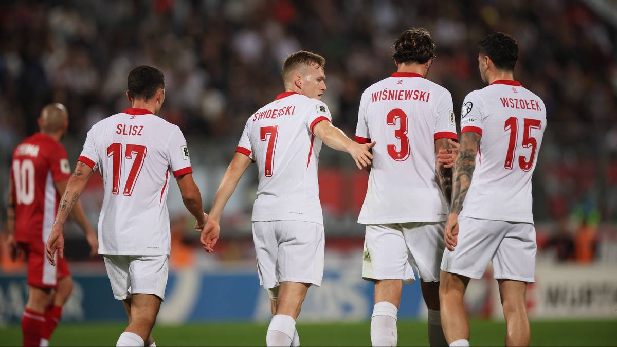 Czterech piłkarzy reprezentacji Polski w białych strojach meczowych z widocznymi numerami na plecach.