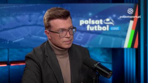 Mężczyzna w okularach i golfie, ubrany w marynarkę, siedzi w studiu telewizyjnym Polsat Futbol.
