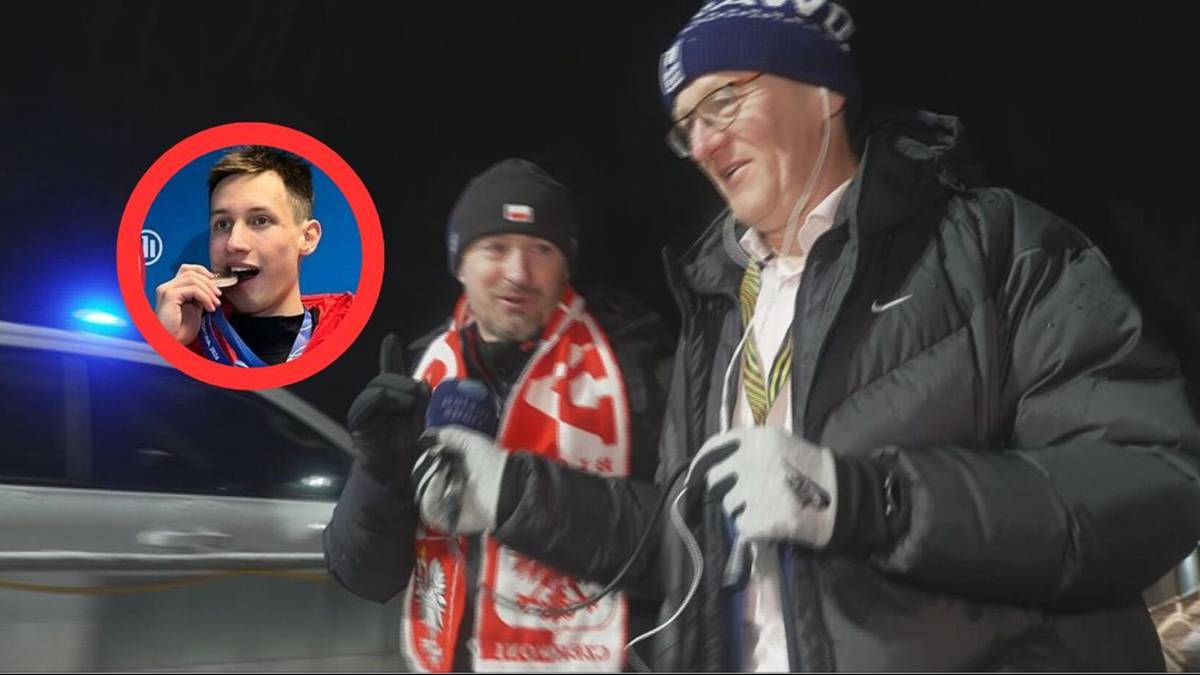 Adam Małysz, prezes Polskiego Związku Narciarskiego, udziela wywiadu, w tle widoczna jest wstawka ze zdjęciem Kacpra Tomasiaka trzymającego medal olimpijski.