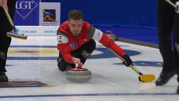 Zawodnik curlingu w czerwonej bluzie z kamieniem na lodzie podczas mistrzostw świata