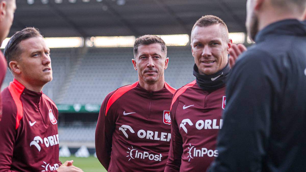 Trzech piłkarzy w koszulkach reprezentacji Polski, w tym Robert Lewandowski, podczas rozmowy.