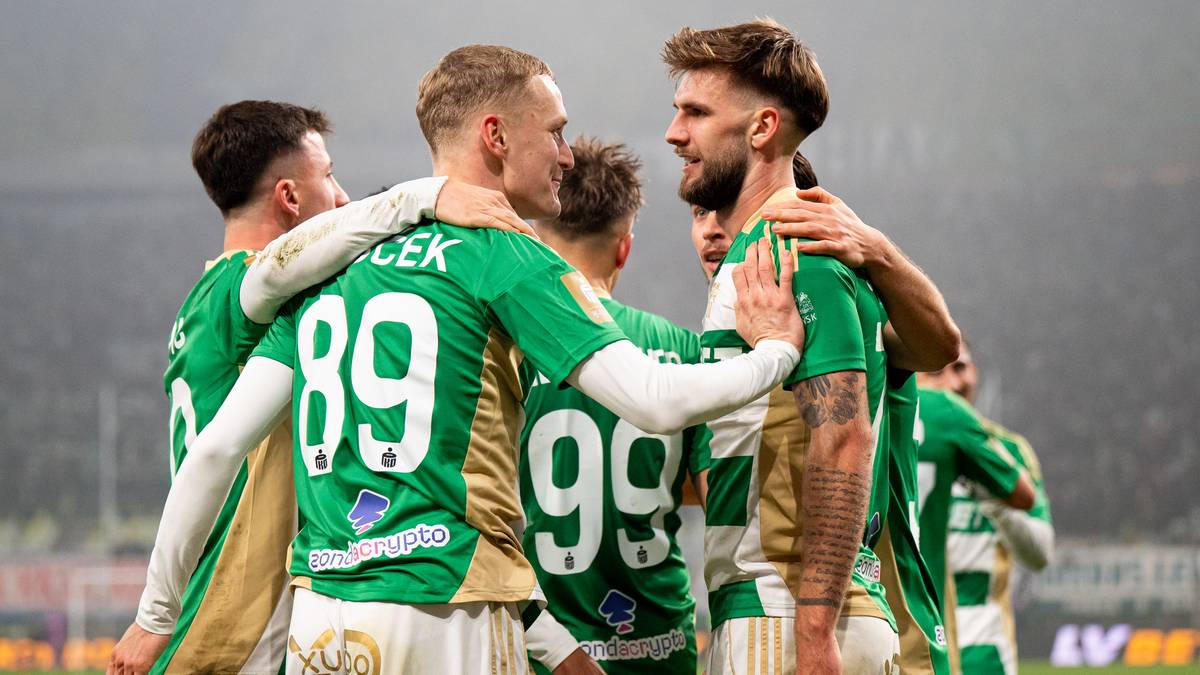 Grupa piłkarzy w zielonych strojach świętująca razem na boisku.