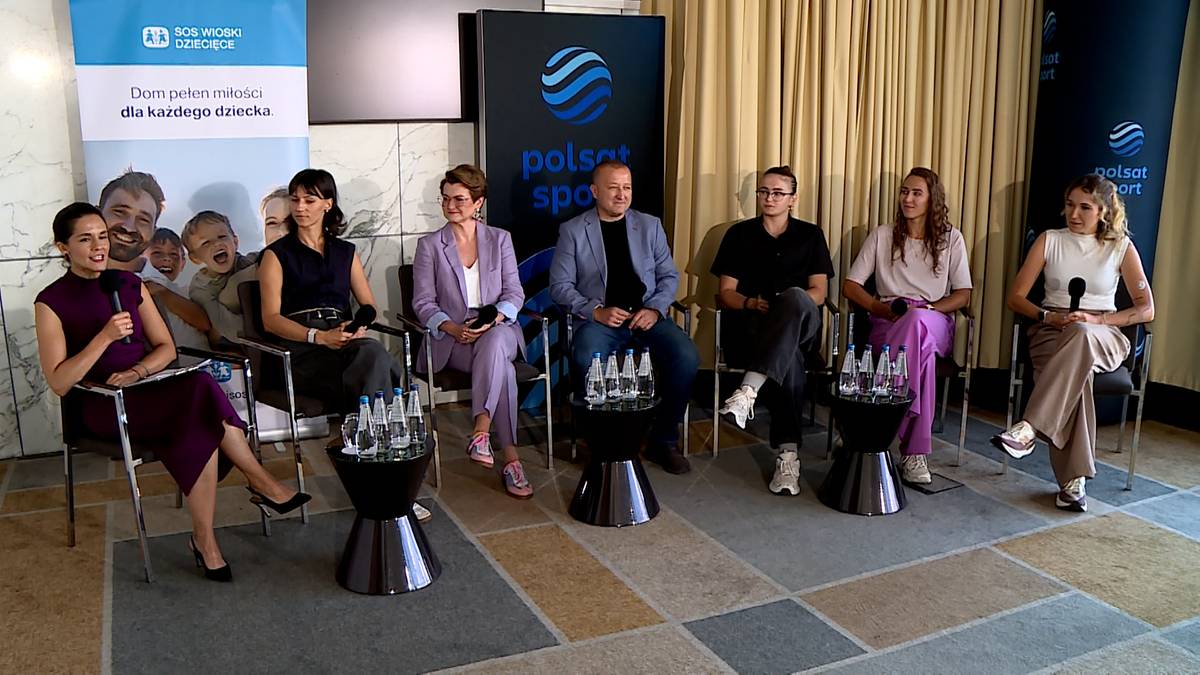 Grupa osób siedzących na krzesłach przed panelami z logo Stowarzyszenia SOS Wioski Dziecięce i Polsat Sport.