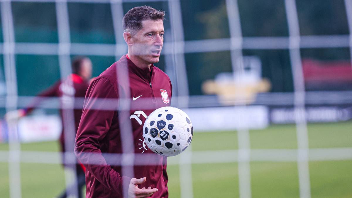 Robert Lewandowski, piłkarz reprezentacji Polski, trzyma piłkę na boisku treningowym.