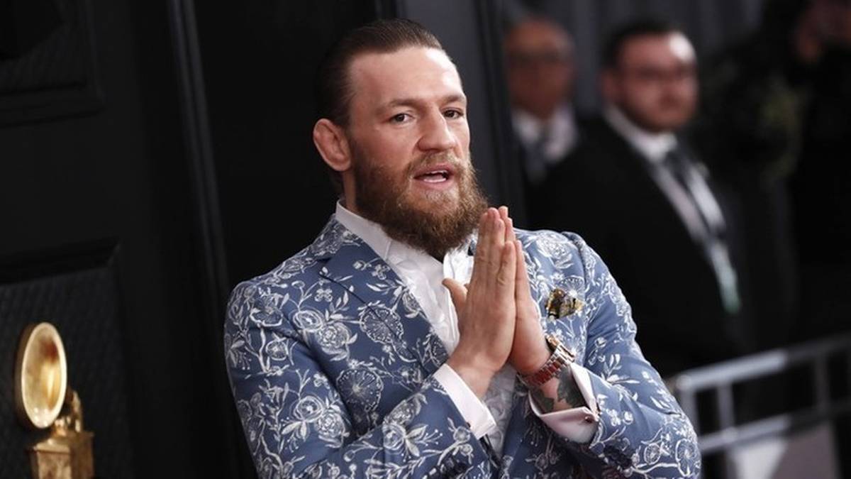 Conor McGregor w ozdobnym garniturze z dłońmi złożonymi przed sobą.