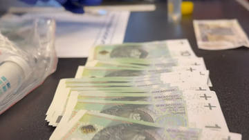Stos fałszywych banknotów o nominale 100 zł z napisem "souvenir" leży na stole.