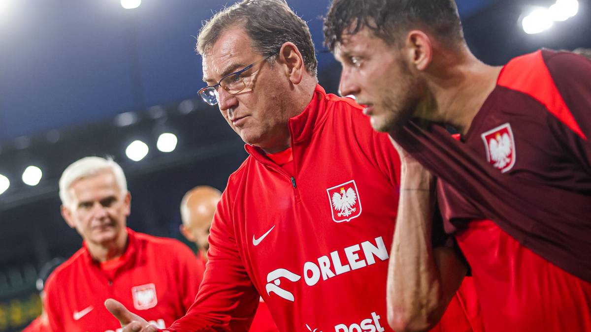 Trener w czerwonej bluzie z napisem ORLEN rozmawia z piłkarzem w czerwonej koszulce reprezentacji Polski.