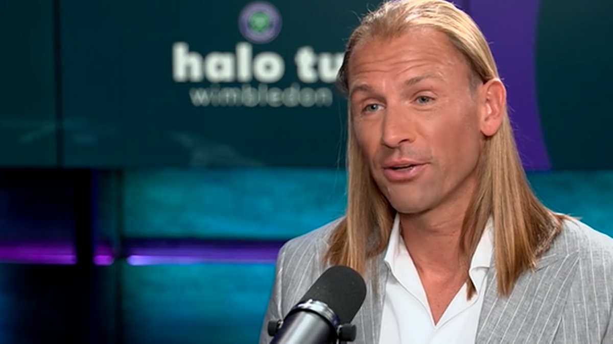 Mężczyzna o długich blond włosach, Łukasz Kubot, udzielający wywiadu.