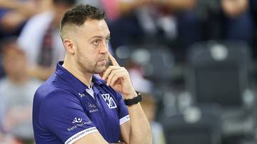 Mężczyzna w niebieskiej koszulce sportowej patrzy w bok z zamyśloną miną.