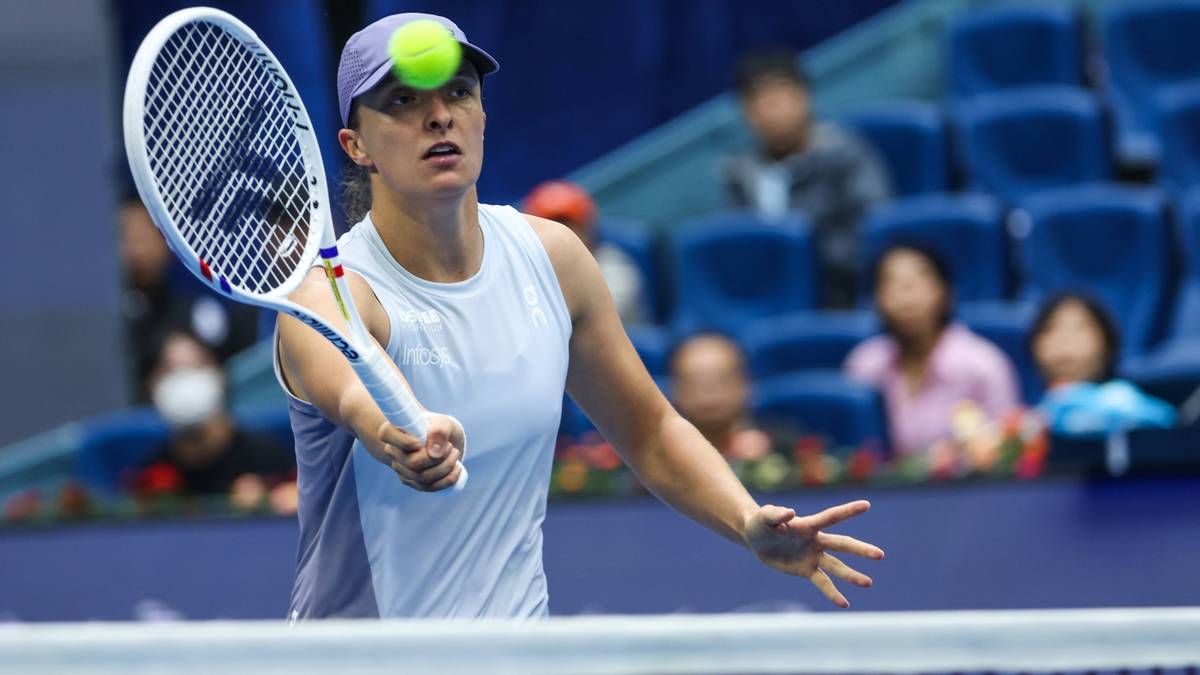 Tenisistka Iga Świątek podczas meczu, z piłką na czole i rakietą w dłoni.